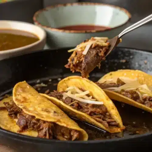 Crockpot Birria Tacos (Easy & Authentic) – The Ultimate Slow Cooker Recipe Crispy birria tacos being fried in a skillet, filled with shredded beef and melted Oaxaca cheese.