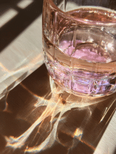Pink salt diet glass reflection on wooden table in sunlight